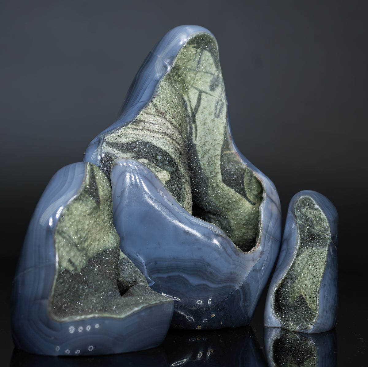 A sculptural agate formation with blue-grey banded chalcedony and green moss inclusions, resembling a small mountain.